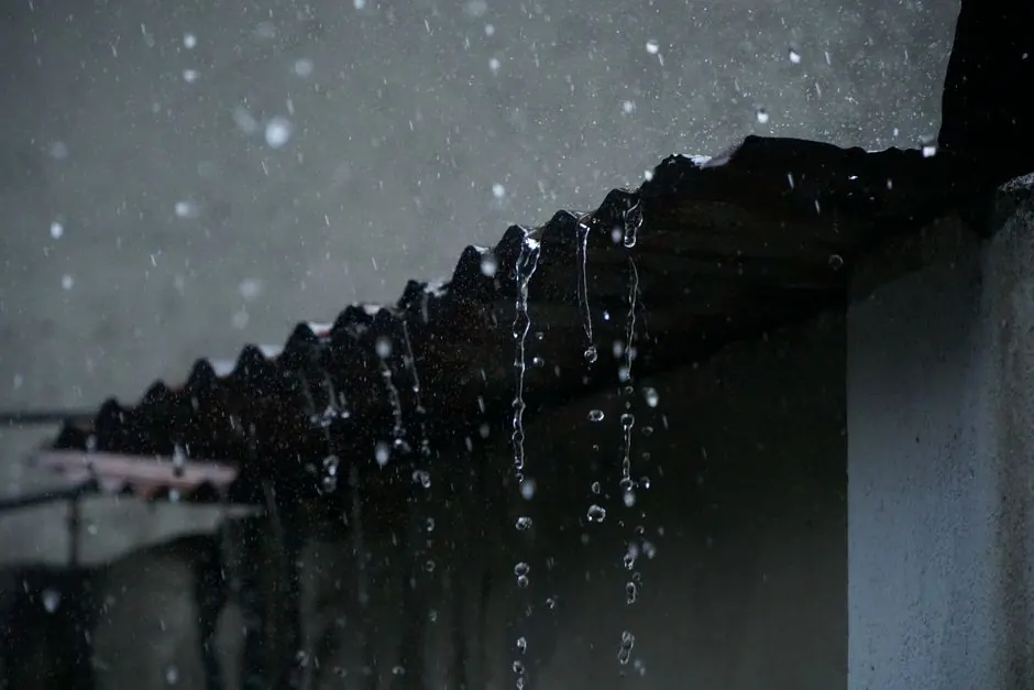 Close-up of rainwater cascading from a corrugated roof in Long Khánh, Vietnam.